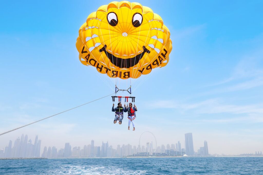 Couple holding hands under deployed parachutes over Hawaiian coastline