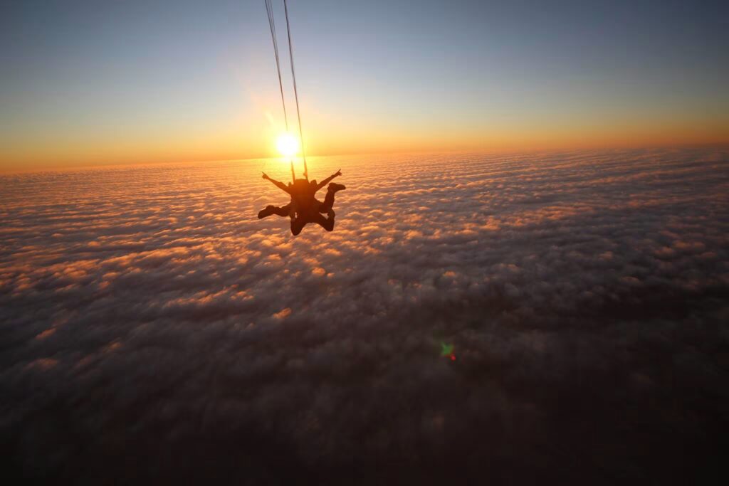 Skydiver above Namibian desert dunes at sunset