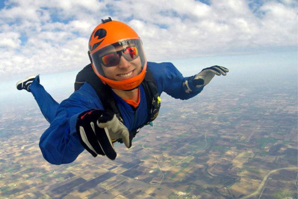Solo student skydiver performing stable freefall with clear blue sky background