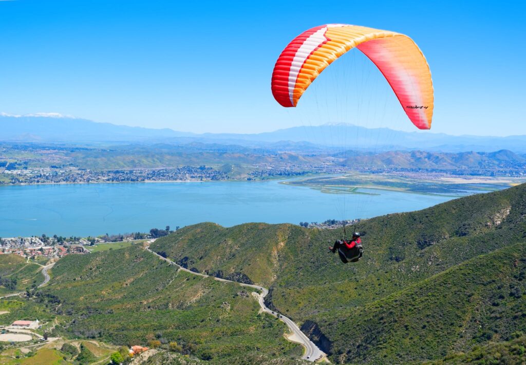 Aerial view of Lake Elsinore with skydiver in foreground, mountains and lake visible below