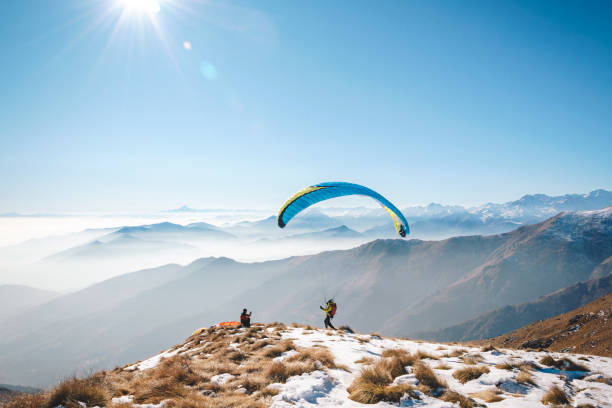 Couple embracing after tandem paragliding experience with mountains in background