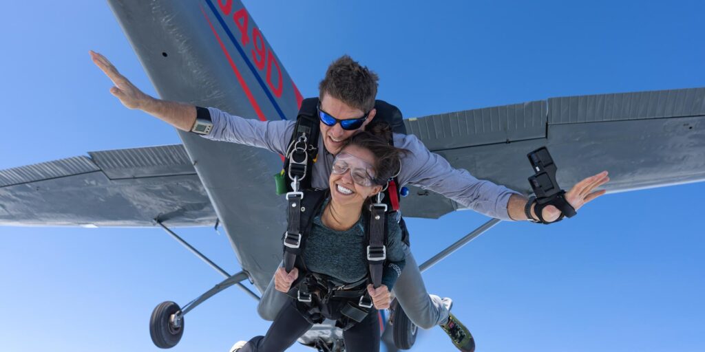 Tandem skydivers exiting aircraft with instructor